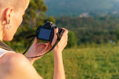 Dijital bir refleks fotoğraf makinesi tutan ve ekranına bakan tanınmamış bir insan..