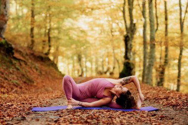 Kadın sonbaharda ormanda minderde yoga yapıyor. sağlıklı yaşam tarzı kavramı