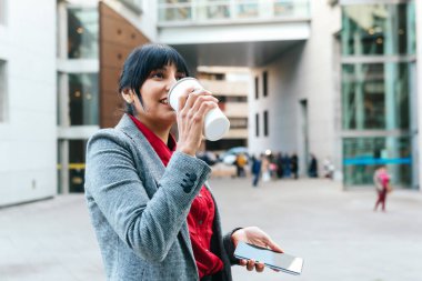 Latin iş kadını işten çıkarken elinde telefonuyla kahve içer..