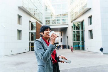 İspanyol iş kadını işten çıkarken elinde telefonuyla kahve içer..