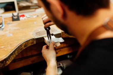 Bir parça gümüşün üzerinde pusula kullanarak mücevher yapan tanınmaz bir adam. Bir atölyede çalışan bir kuyumcu..