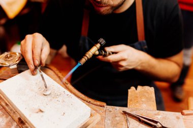 Bir mücevheri şekillendirmek için kaynak makinesiyle çalışan tanınmamış bir adam. Usta kuyumcu atölyesinde çalışıyor. arts, el sanatları ve küçük işletmeler