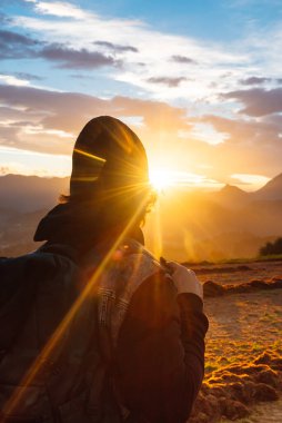 Sırt çantalı bir adam dağlarda yürüyüş yaparken gün batımını seyrediyor. seyahat ve sağlıklı yaşam tarzı.