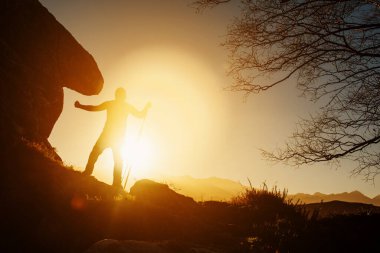 Gün batımında dağda elastik bantlarla egzersiz yapan bir adamın silueti. sağlıklı yaşam tarzı.