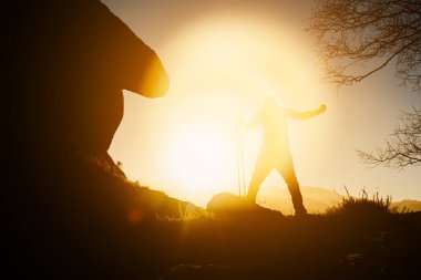 Gün batımında dağda elastik bantlarla egzersiz yapan bir adamın silueti. sağlıklı yaşam tarzı.