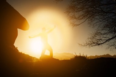 Gün batımında dağda elastik bantlarla egzersiz yapan bir adamın silueti. sağlıklı yaşam tarzı.