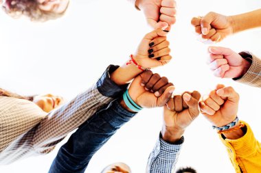 Farklı ırktan ve kültürlerden gelen bir grup insanın yumruklarını birbirine çarpıştırması. Beyaz arka planda birlikte duran çok ırklı kadın ve erkekler..