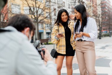 Sokakta tanınmayan bir fotoğrafçı için poz veren iki Latin kadın..