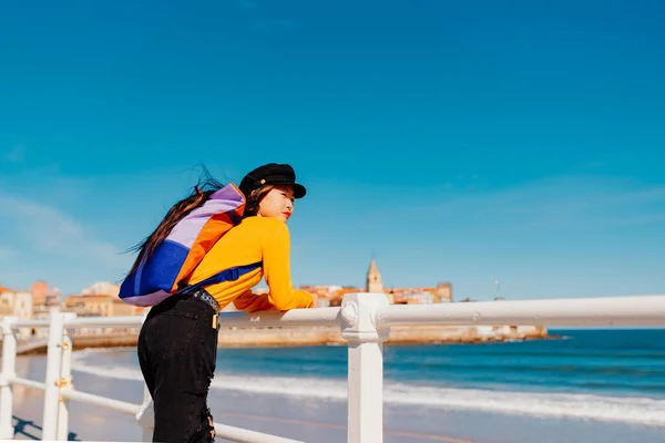 観光中にスペインの街のビーチを見ながらリュックを背負った若いアジア系女性 旅行や観光 スペインのアストゥリアス州ジョン — ストック写真