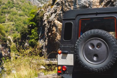 Siyah off-road arabası büyük kayalıkların arasındaki dağ yolundan iniyor. seyahat ve macera
