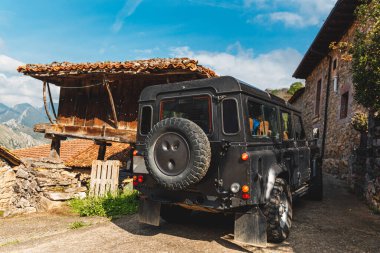 Klasik Off-road 4x4 arabası İspanya 'nın Asteria Dağları' ndaki eski bir kasabadan geçiyor. Horreo, klasik Asturian yapısı..