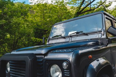 Klasik siyah 4x4 off-road arabasının önünde ormanlık alana park edilmiş. seyahat ve macera