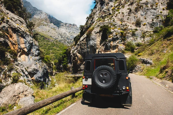 black off-road car descending a mountain road between large stone cliffs. travel and adventure