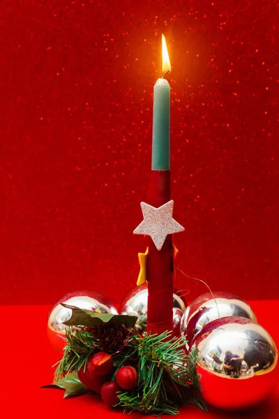 christmas postcard with burning candle decorated with christmas tree balls, stars and holly.