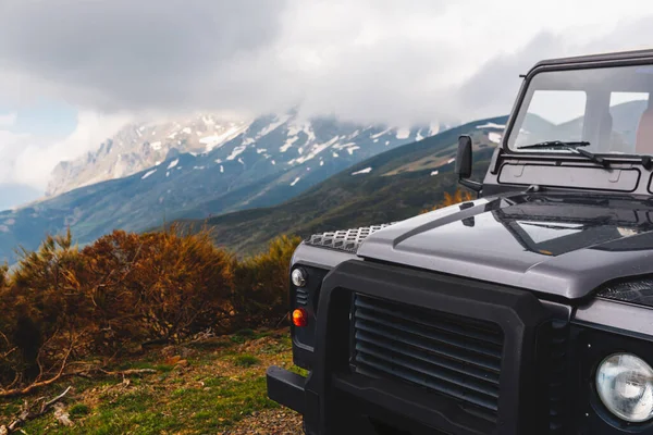 bulutlu bir günde dağlarda toprak yolda siyah bir off-road arabası. Seyahat ve macera