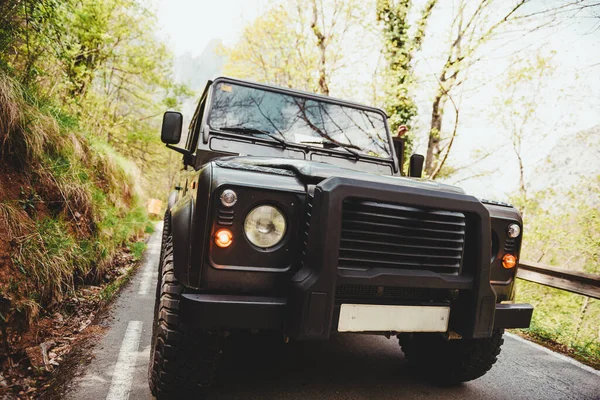 front of black off-road car descending a road through a forest. concept of adventure travel