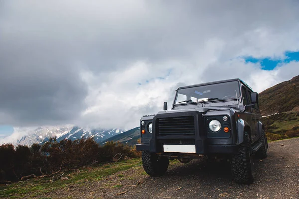 bulutlu bir günde dağlarda toprak yolda siyah bir off-road arabası. Seyahat ve macera