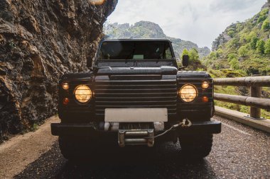 Dağdaki siyah off-road arabasının ön tarafında ışıklar açık.