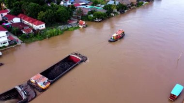 Nehirde bir römorkör var. Küçük bir gemi nehirde malları taşıyor. Drone görüntüleri.