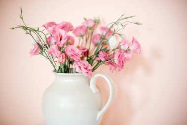 Östomalı buket, beyaz vazoda yaz çiçekleri, pembe-bej arka planda..