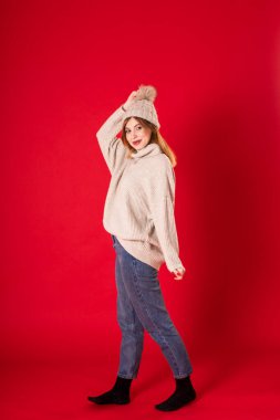 Kırmızı arka planda şapkalı ve açık renk süveterli bir kız.