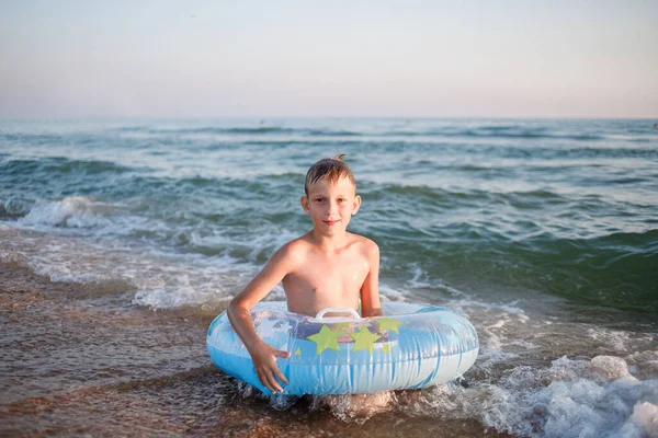 Chlapec s gumovým kroužkem na pobřeží — Stock fotografie