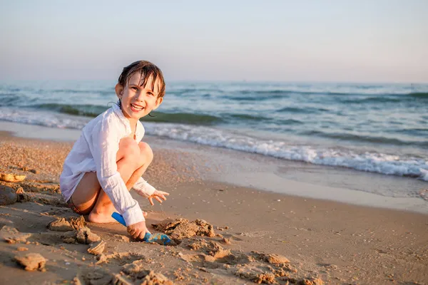 Παιδί Ευρωπαίος κάθεται στην παραλία δίπλα στη θάλασσα — Φωτογραφία Αρχείου