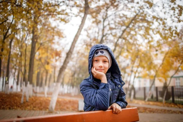 Ένα αγόρι με μπλε σακάκι περπατάει σ 'ένα πάρκο το φθινόπωρο. — Φωτογραφία Αρχείου
