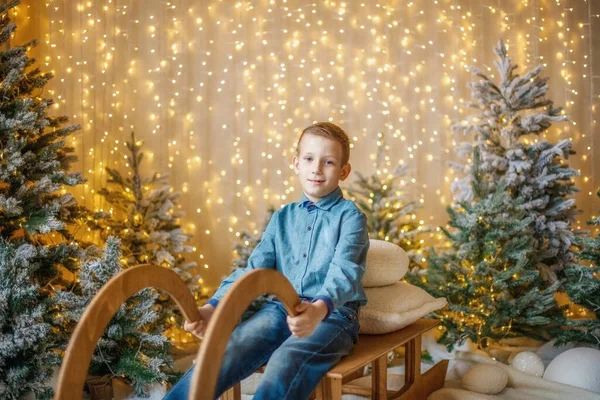 Un enfant sur un traîneau parmi les arbres dans les décorations du Nouvel An. — Photo