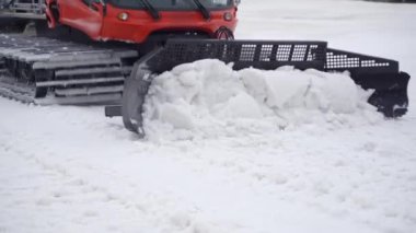 Yakın plan kar aracı karlı dağları tırmıklıyor. Kar yamaçları kayak için hazırlanıyor