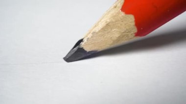 Tahta kırmızı grafit kalem beyaz kağıda bir çizgi çizer.