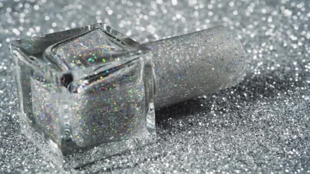 Slow movement along the silver glitter nails polish in bottle. Shiny background — Stock Video