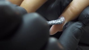 Parlak gümüş ojeli fırça kadınların tırnaklarına oje sürmek için