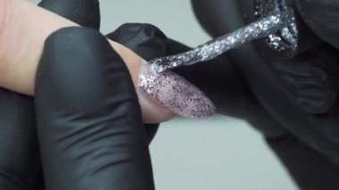 Manikür ustası müşteriyi gümüş cila ile kaplıyor. Yüksek kalite 4k görüntü