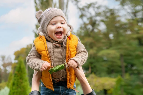 Un pequeño bebé lanzando al aire libre en el parque de otoño. Mamá lanza al cielo a su pequeño bebé sonriente. Familia feliz — Foto de Stock