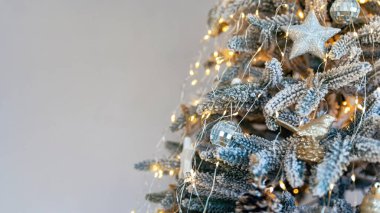 Gri arka planda güzel dekore edilmiş Noel ağacı. Modern noel ağacı süsleri ve altın noel ışıkları bokeh. Yeni yıl konsepti. Metin için boşluk.