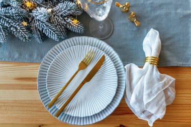 Ahşap masada güzel bir Noel masası. Altın ve mavi renkte Noel yemeği için şenlikli bir yer. Üst görünüm