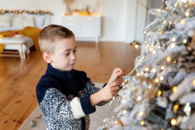 Odada Noel ağacı süsleyen beyaz, şirin bir çocuk var. Xmas partisi kutlaması. Yeni yıl atmosferi ve tatil havası kavramı.