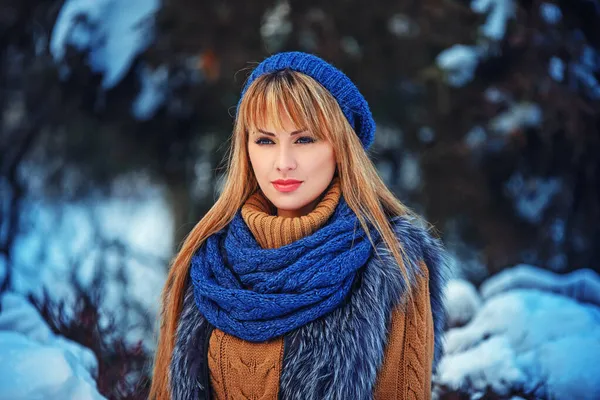 Талия до портрета очаровательной молодой женщины, гуляющей в снежном парке в теплой одежде. Милая счастливая блондинка в трикотажной шляпе и огромном шарфе позирует в зимнем лесу — стоковое фото
