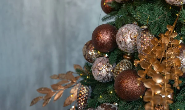 Gedecoreerde kerstboom op grijze achtergrond. Brons en gouden kerst ornamenten sparren boom brunch close-up. Ondiepe focus. Wintervakantie wallpaper concept. Kopieerruimte. — Stockfoto
