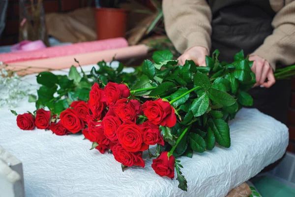 Fleuriste féminine créer un bouquet de roses rouges fraîches sur le lieu de travail. Concept de boutique florale. Un beau bouquet frais. Livraison de Fleurs. — Photo