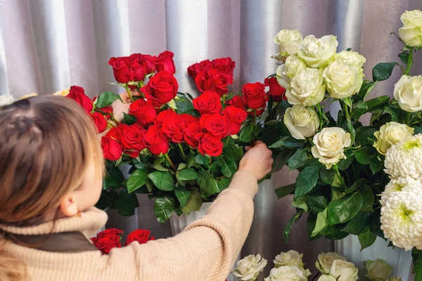 Floristics, business, decoration concept. Flower store salesperson arranging rose flowers. Back view of female shop assistant. Florist selects flowers for making bouquet. — Stock Photo, Image