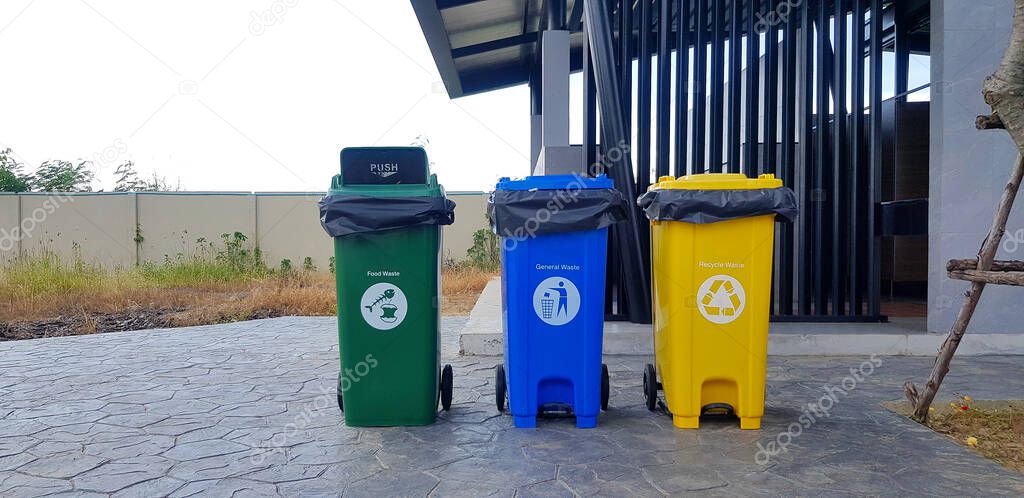 Colorful three bins (Green, blue, yellow) for separate trash for reuse and disposal in front of public toilet or washroom. Trash Can for dumping used stuff or material on street, road or footpath.