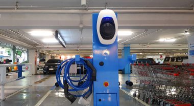 Bangkok, Tayland - 25 Mart 2022: Alışveriş merkezindeki park yerinde şarj aleti ve telle çalışan elektrikli arabalar için mavi şarj noktası istasyonu. Teknoloji ve Temiz Enerji Konsepti