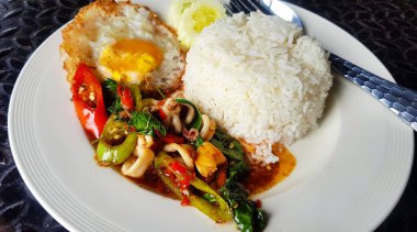 Tayland usulü kalamar ve sahanda yumurta ile karıştırılmış fesleğeni beyaz tabakta ya da Tayland restoranında servis et. Pirinçli baharatlı yemek. Asya 'da meşhur yemek..
