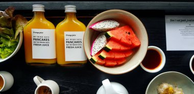 Tabakta taze karpuz ve ejderha meyvesi, portakal suyu, Çin mantısı, siyah ahşap masada tatlı sos. Ahşap zemin üzerinde sebze ve meyve yatağı. 