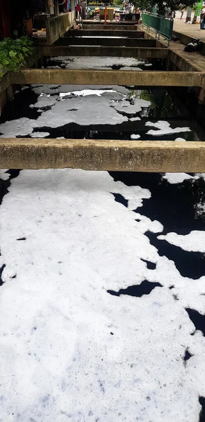 White pollution bubbles or detergent bubbles float in the community on the river. The filthiness and bad habits of human beings damage the environment or nature.