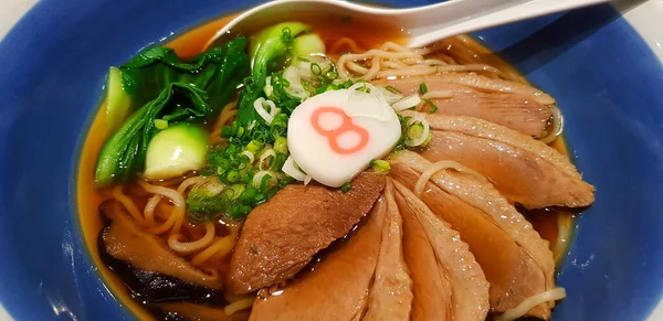 将热腾腾的拉面与蔬菜 切碎的葱和煮好的鸭放入蓝色碗中的汤中 亚洲著名的日本食品 — 图库照片