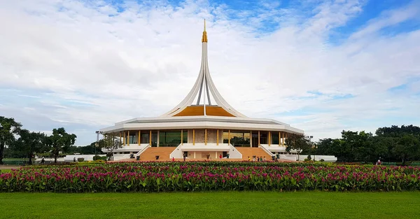 Beautiful white building with purple or violet flower garden foreground and blue sky background at  Suan Luang Rama IX Bangkok, Thailand. Architecture and nature with cloudscape.