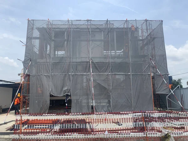 İnşaat işçisi mavi arka planı olan bir bina ya da daire inşa ediyor. Mühendis, toz veya endüstriyel konseptin düşmesini ve dağılmasını önlemek için kamufle olarak çalışıyor..